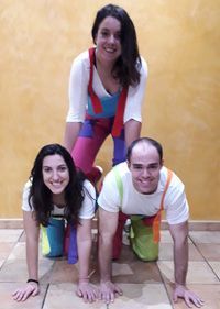 Un hombre y dos mujeres están haciendo una pirámide en el suelo.