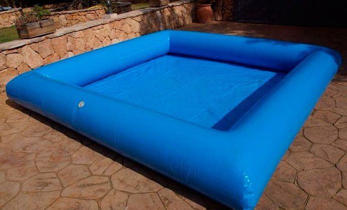 Una gran piscina inflable azul está ubicada en un patio.