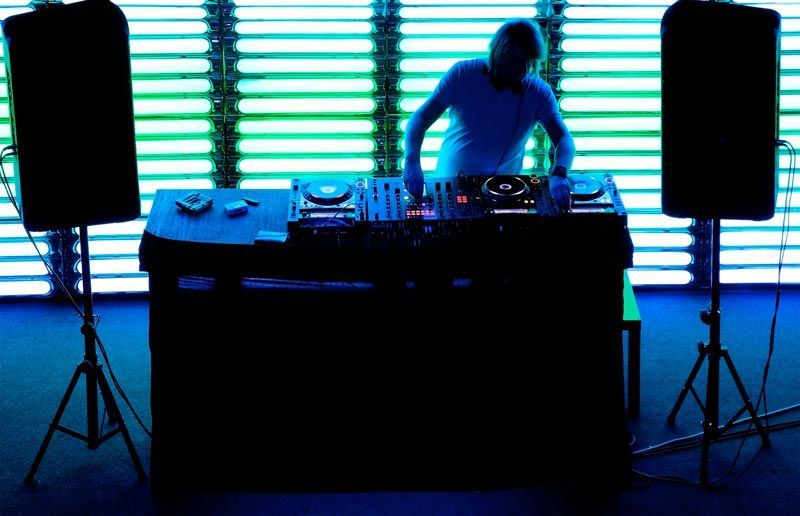 Un DJ está tocando música en una mesa frente a una ventana.