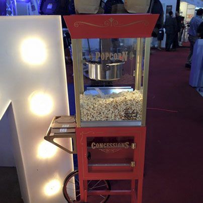 Una máquina de palomitas de maíz en un carrito que dice concesiones.