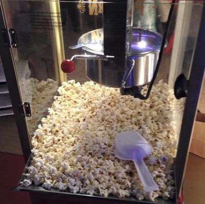 Una máquina de palomitas de maíz llena de palomitas de maíz y una cuchara