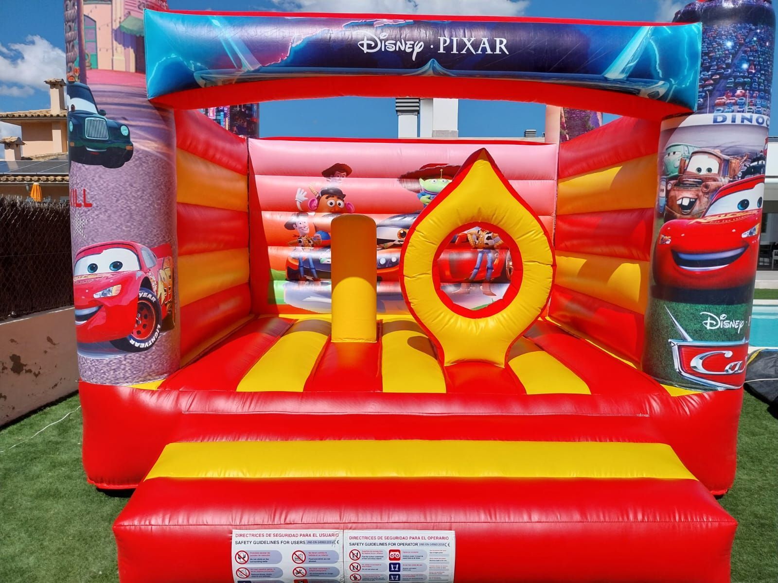 Una casa inflable roja y amarilla con autos encima.