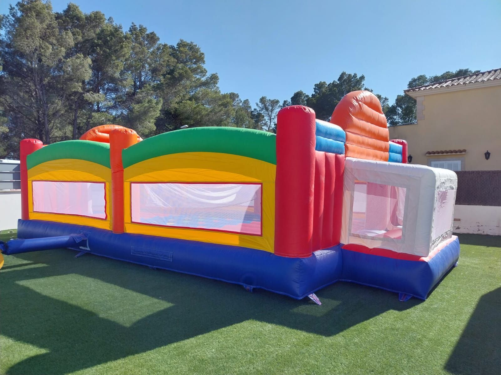 Una casa inflable colorida se encuentra en la parte superior de un exuberante campo verde.