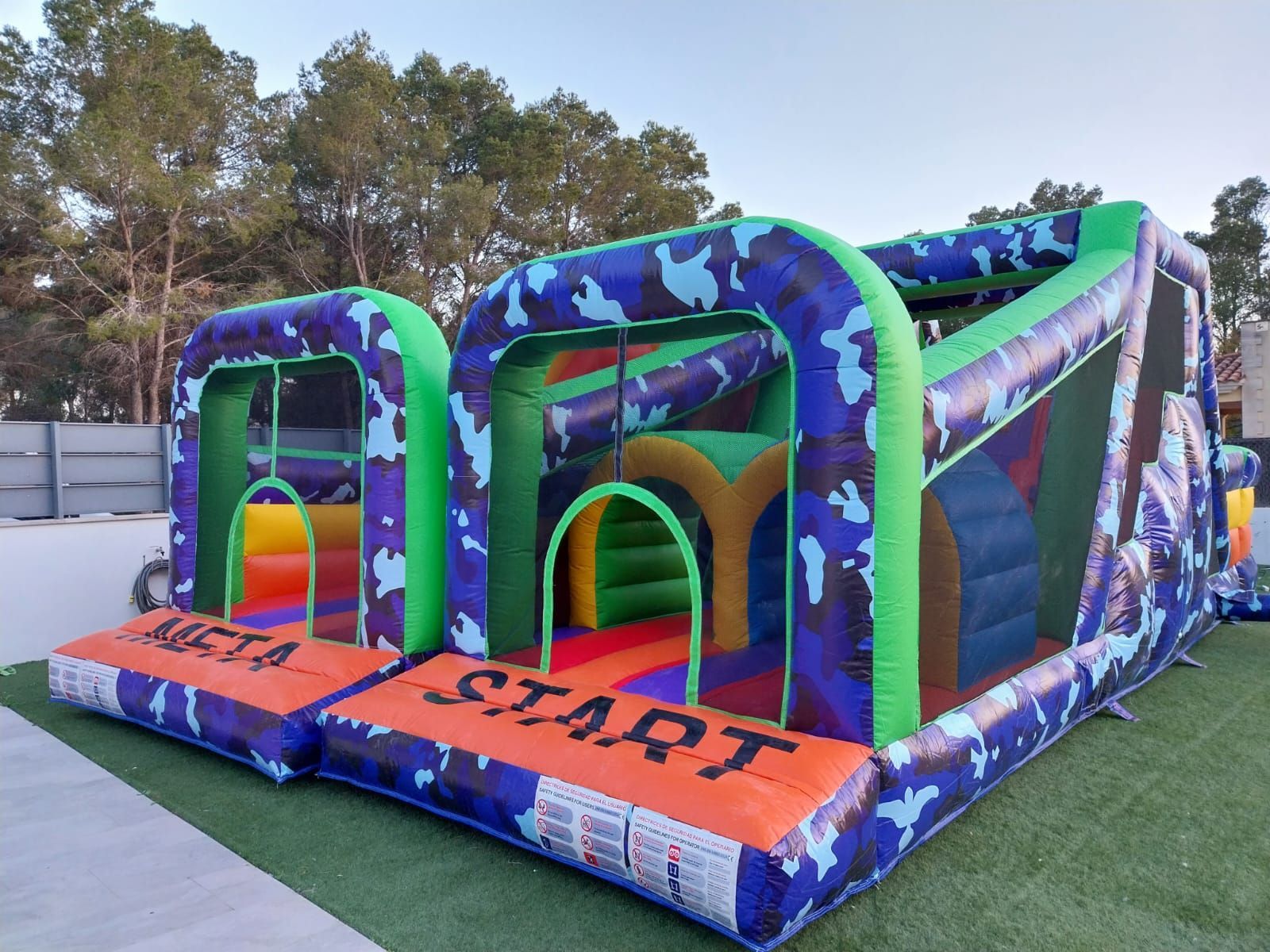 Una gran carrera de obstáculos inflable se encuentra sobre un exuberante campo verde.