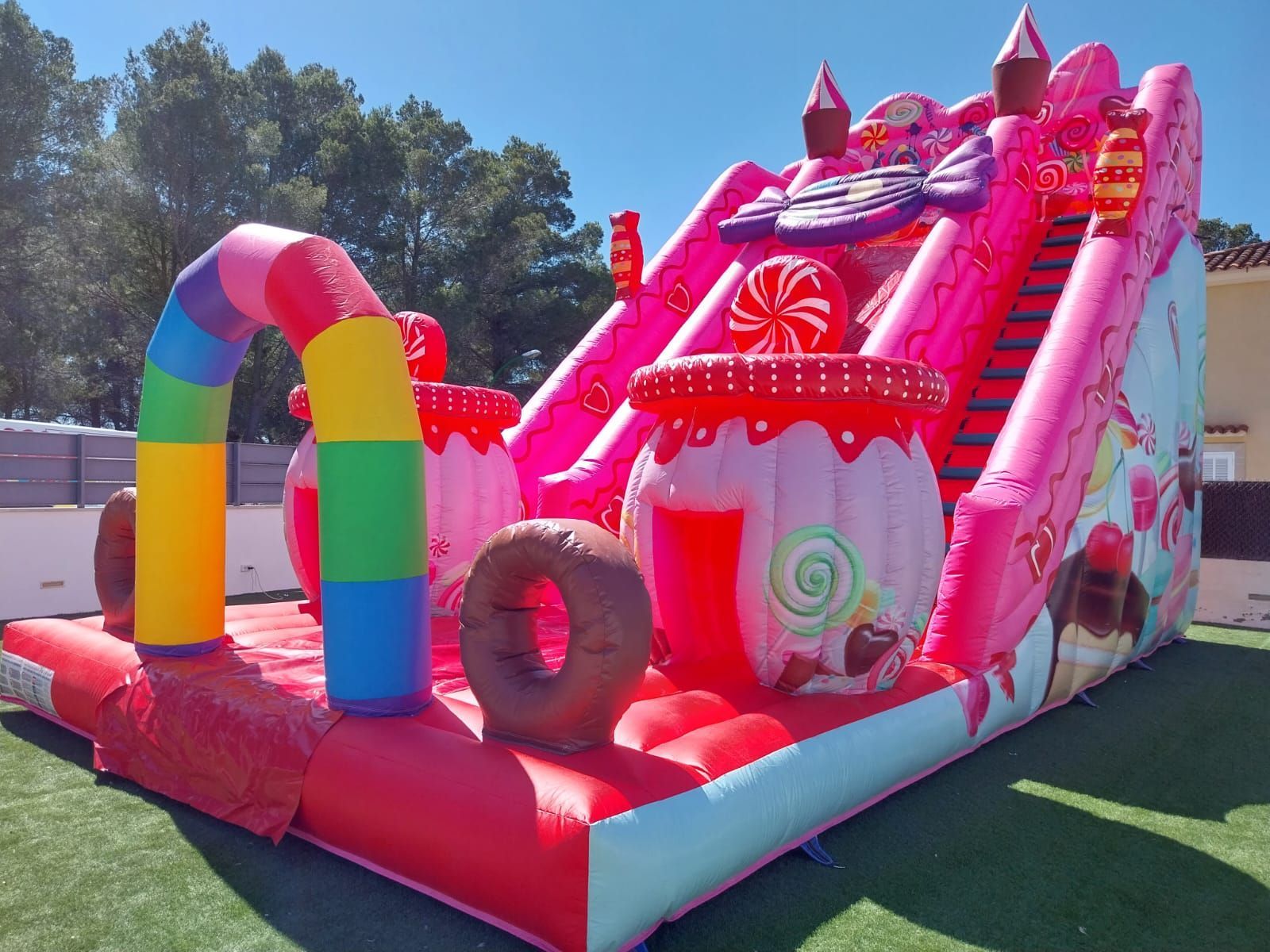 Una casa inflable rosa y blanca con dulces encima.