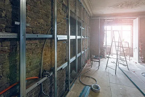 Se está remodelando una habitación con paredes de ladrillo y una escalera.