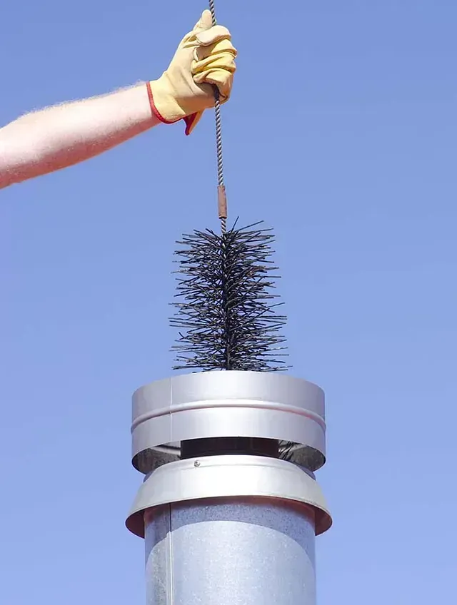 Una persona está limpiando una chimenea con un cepillo.