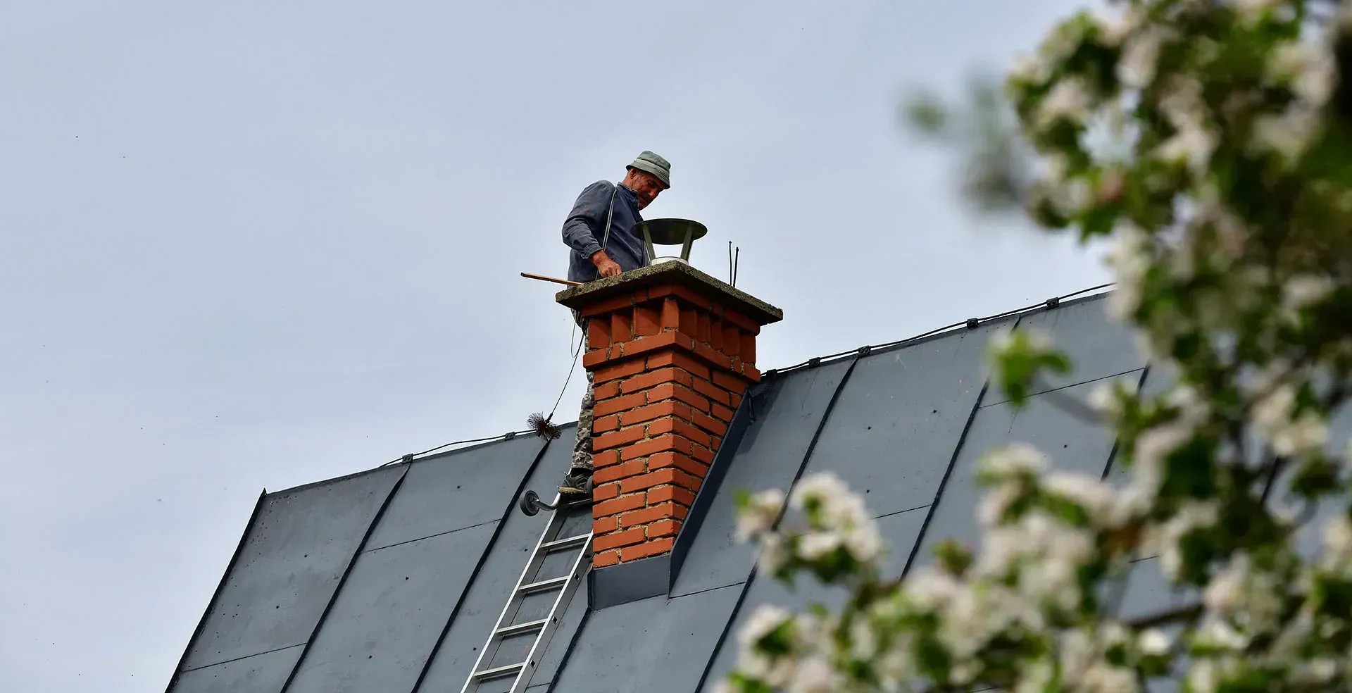 Un hombre está de pie sobre un tejado, al lado de una chimenea.