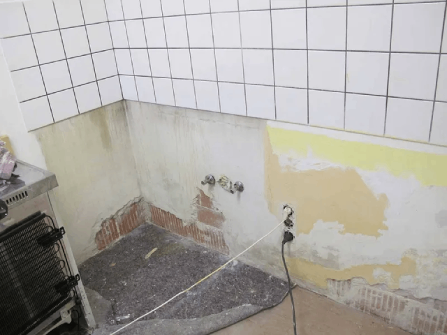 Eine Küche mit weißen Fliesen und einem Herd.