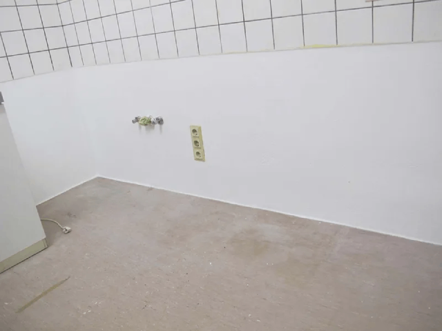 Ein Badezimmer mit weißen Fliesen und grauem Boden.