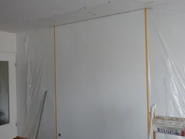 Ein Raum mit einer großen weißen Wand und einer Leiter.