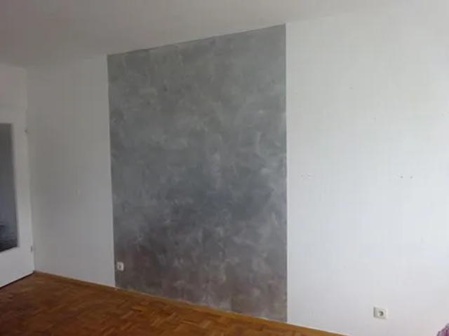 Ein Wohnzimmer mit einer grauen Wand und einem Holzboden.