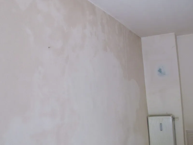 Ein Raum mit einer weißen Wand und einem Spiegel.