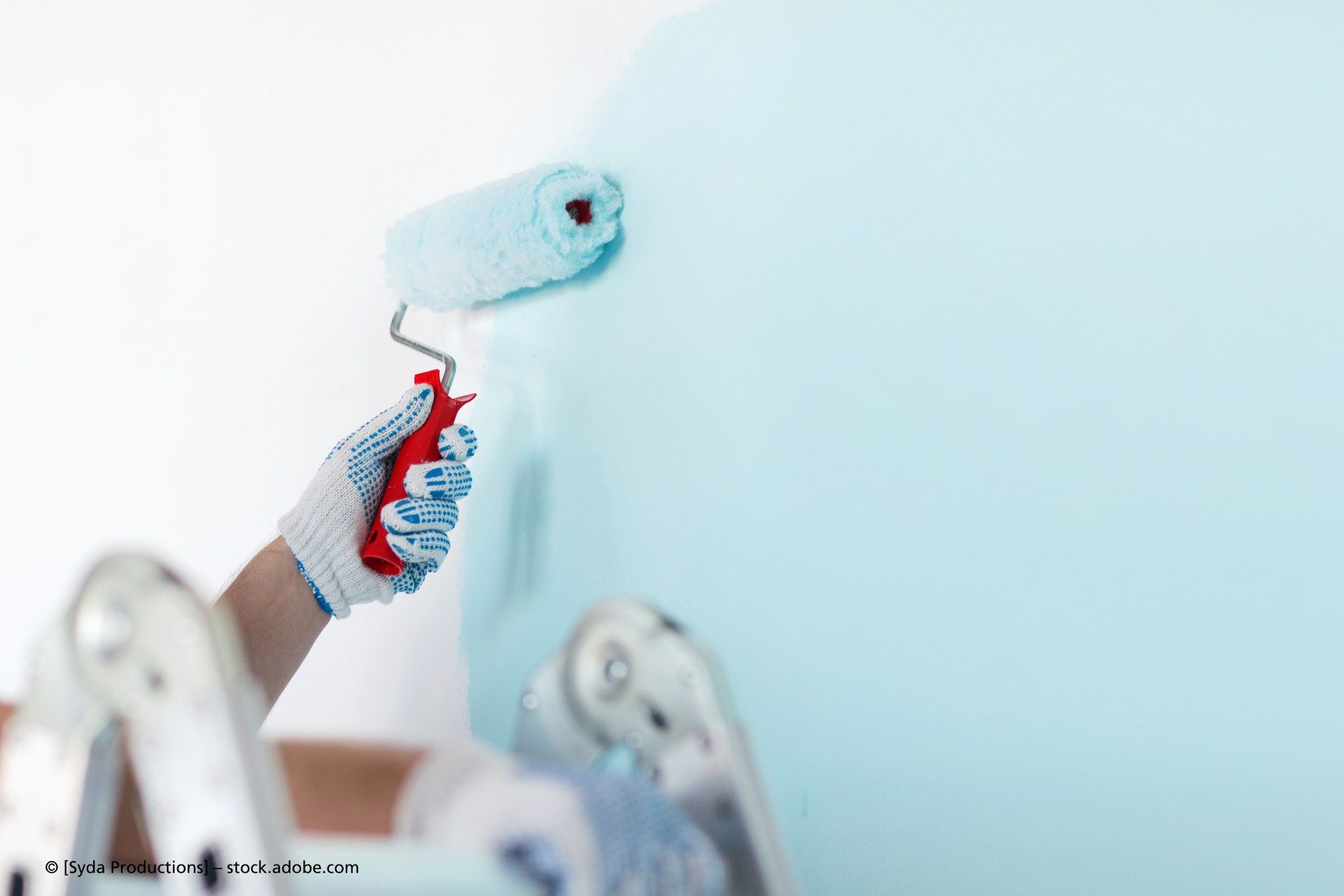 Eine Person streicht eine Wand mit einer Farbrolle.