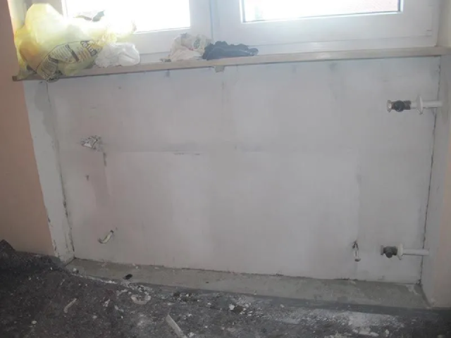 Eine weiße Wand mit einem Fensterbrett in einem Zimmer.