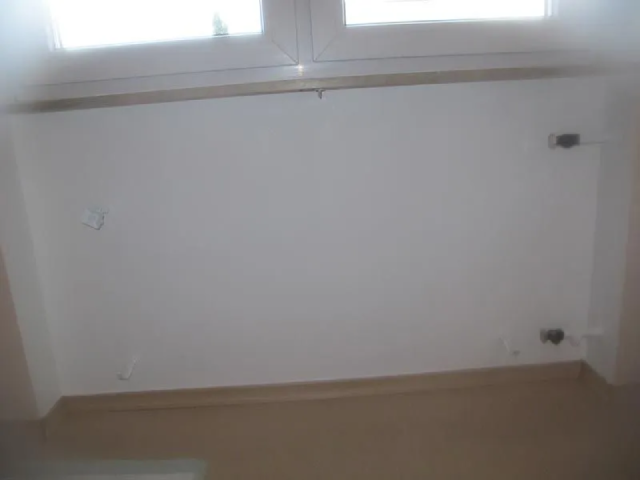 Ein leerer Raum mit einer weißen Wand und einem Fenster.