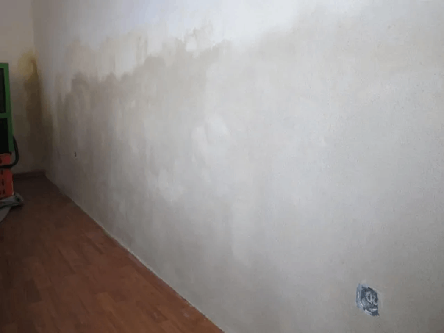 Eine weiße Wand mit einem Holzboden in einem Raum.