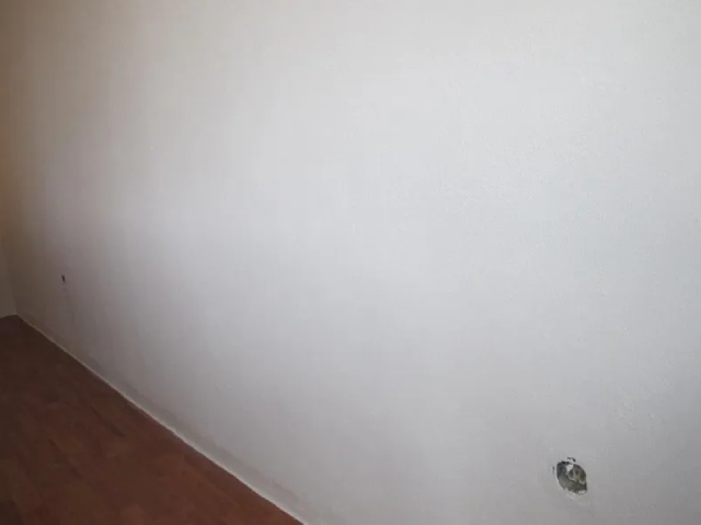 Eine weiße Wand mit einem Lichtschalter in einem Raum.