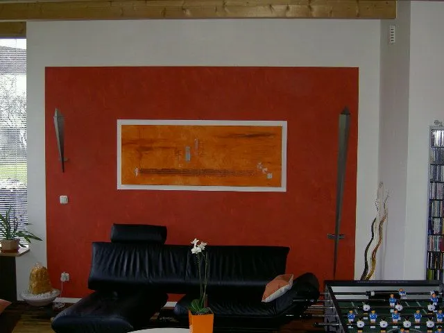 Ein Wohnzimmer mit einer roten Wand und einer schwarzen Couch