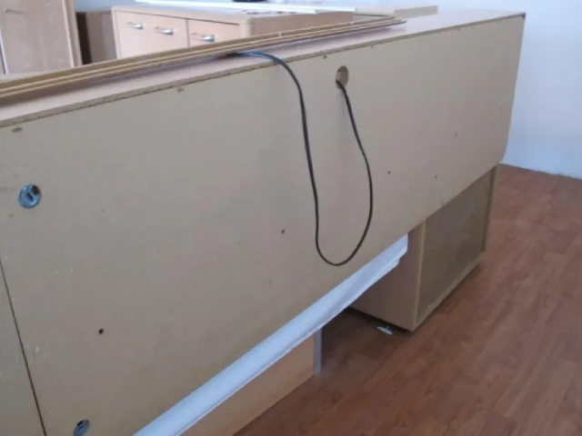 Eine Schnur hängt von der Rückseite eines Holzschranks