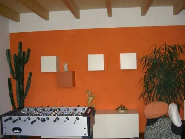 Ein Tischfußballtisch in einem Wohnzimmer mit einer orangefarbenen Wand