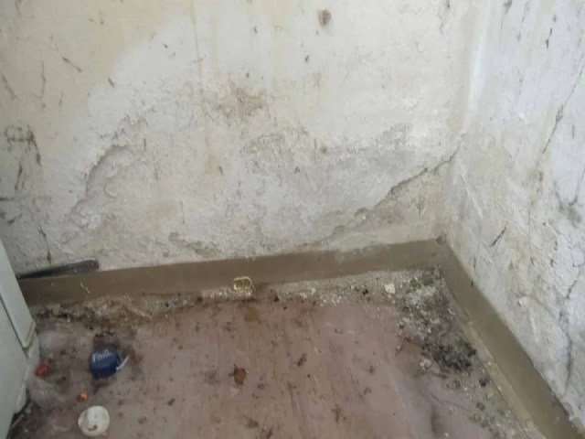 Ein schmutziges Zimmer mit einem schmutzigen Boden und einer schmutzigen Wand.