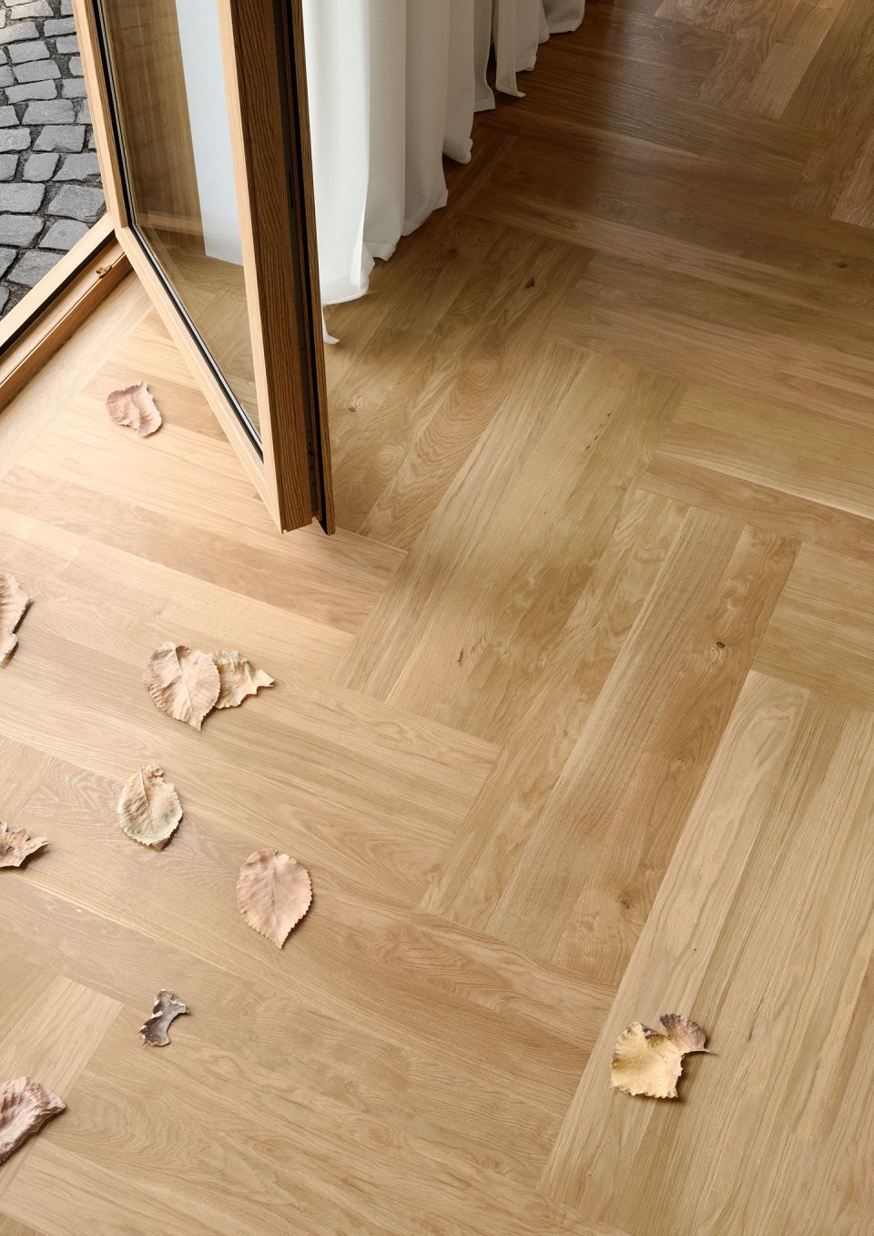 Ein Holzboden mit Blättern darauf und einer Tür im Hintergrund