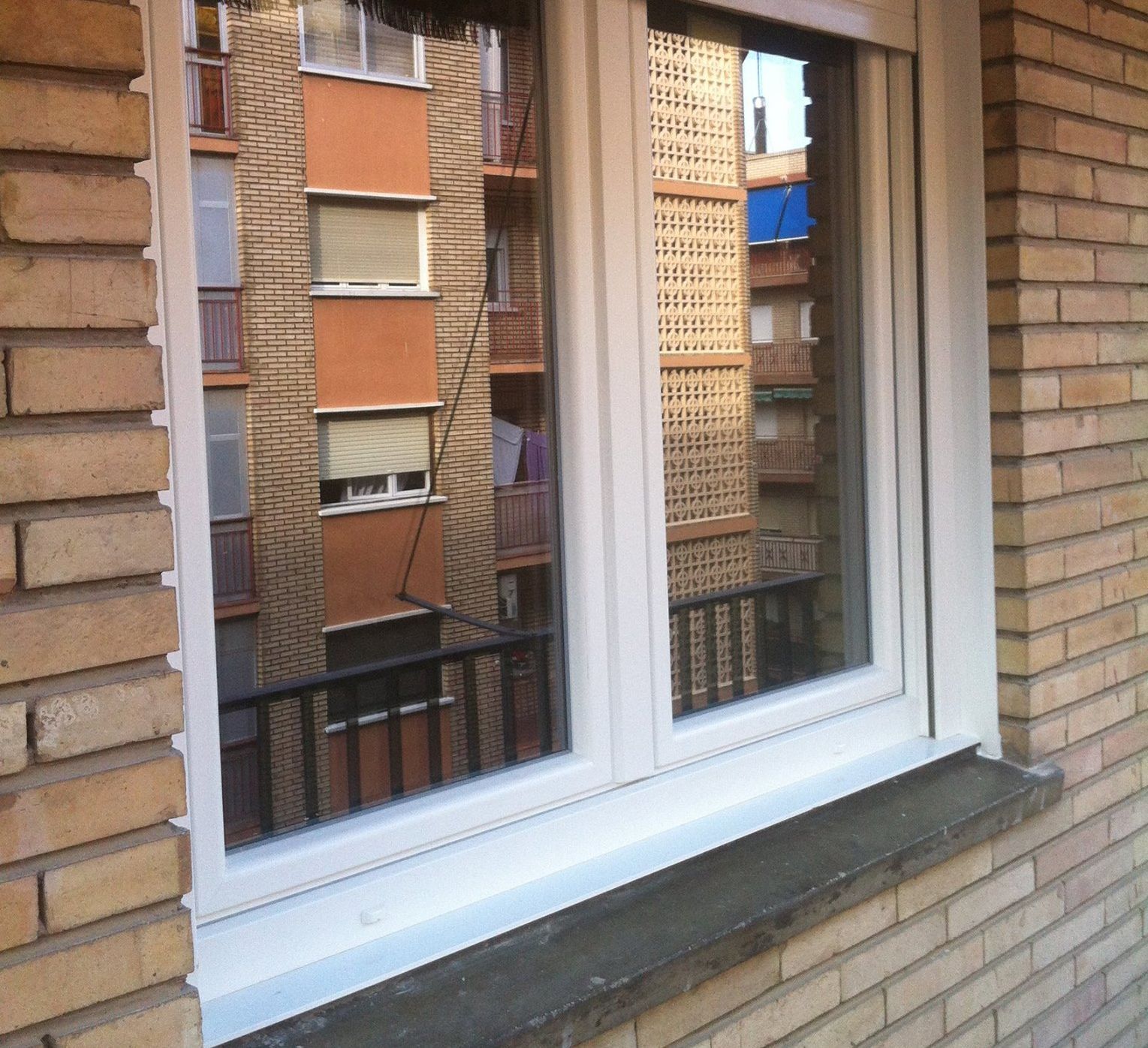 Un edificio de ladrillo con una ventana blanca y un balcón.