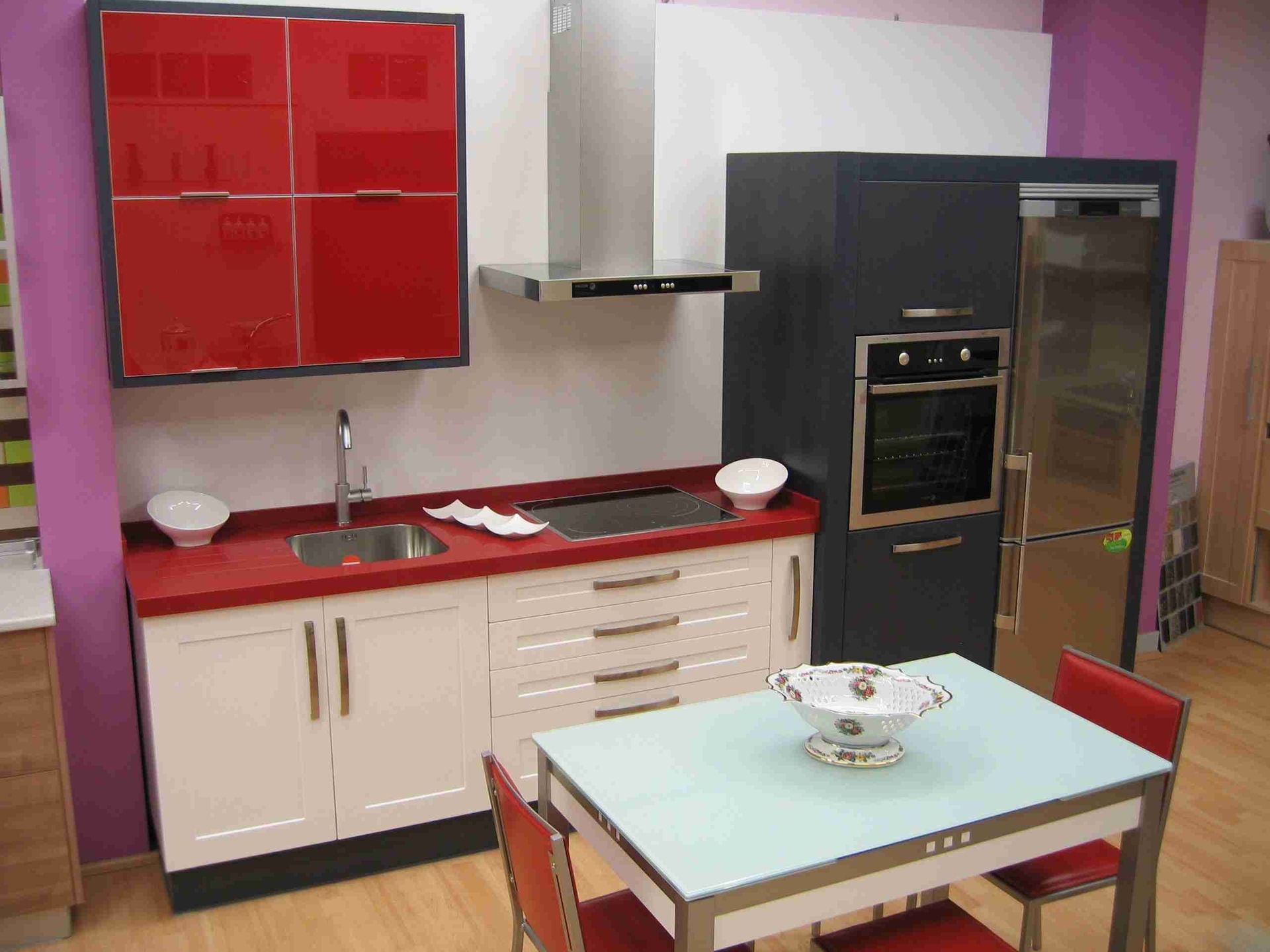 Una cocina con gabinetes rojos y una mesa blanca.