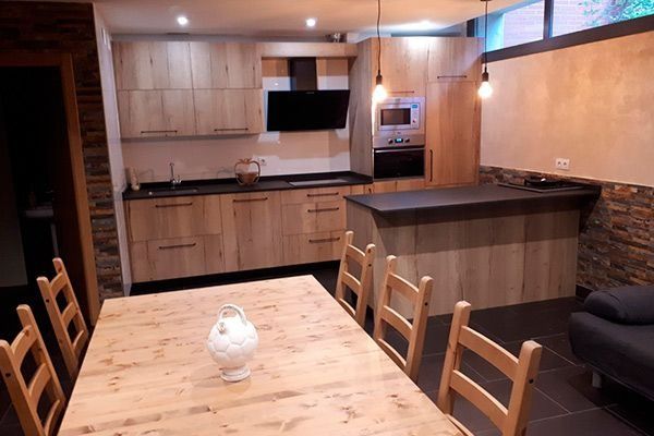 Una cocina con gabinetes de madera y una mesa y sillas de madera.