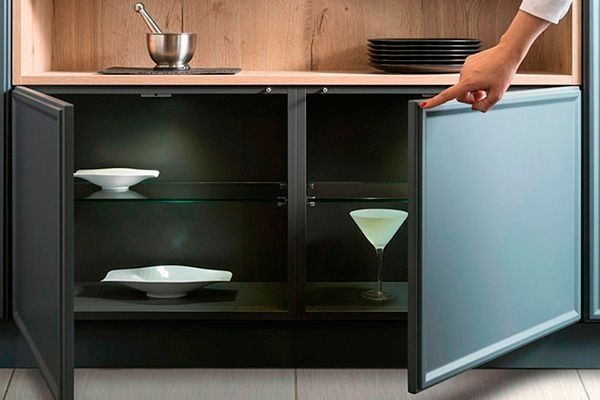 Una persona está abriendo un armario que contiene una copa de martini dentro.