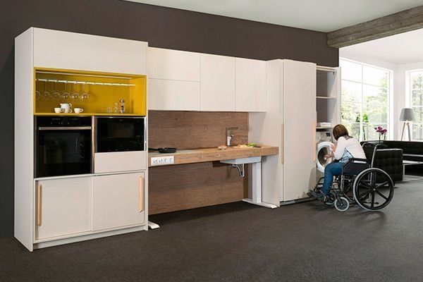 Una mujer en silla de ruedas está sentada en una cocina.