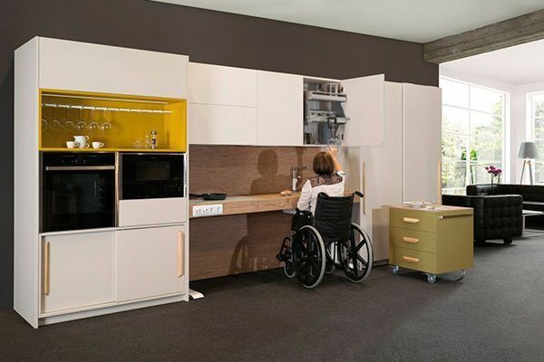 Una mujer en silla de ruedas está sentada en un mostrador en una cocina.