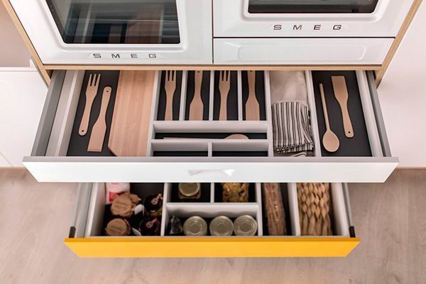 Un cajón de cocina lleno de utensilios y frascos.