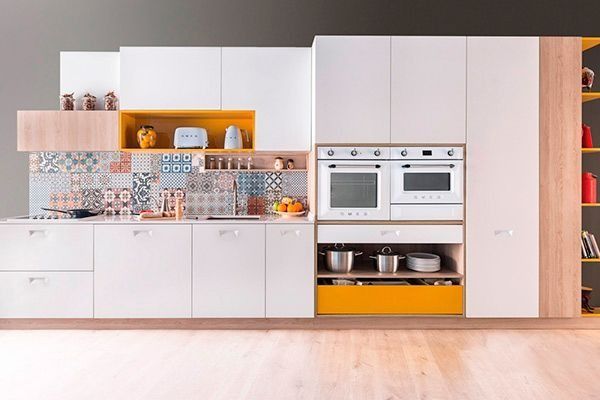 Una cocina con gabinetes blancos, cajones amarillos y un horno blanco.