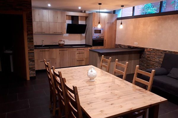 Una cocina con una mesa y sillas de madera y un sofá.