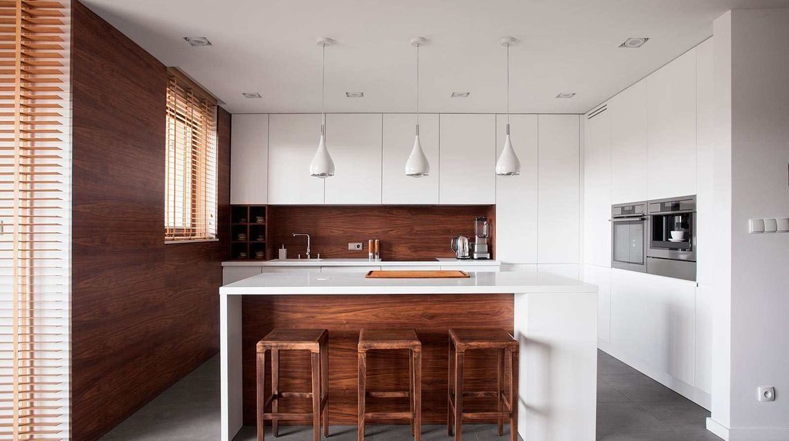 Una cocina con gabinetes blancos y taburetes de madera.