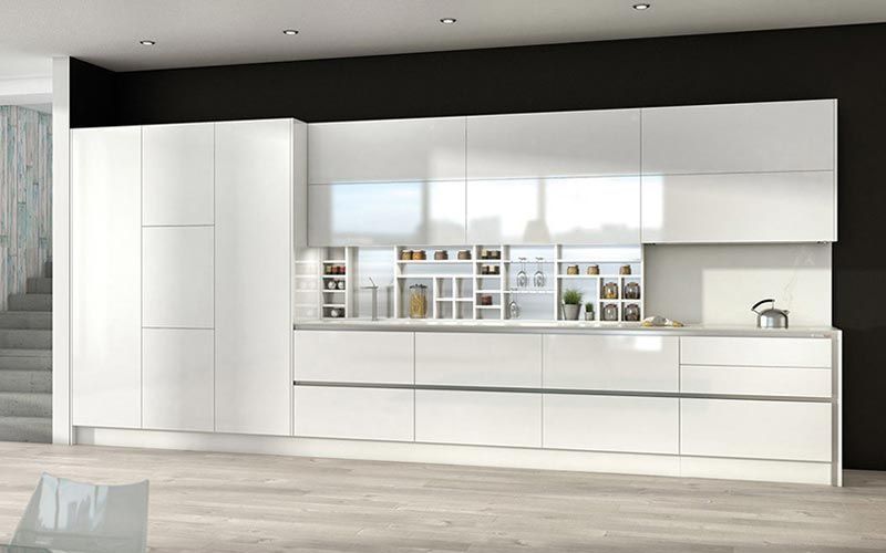 Una cocina con muchos gabinetes y cajones blancos.