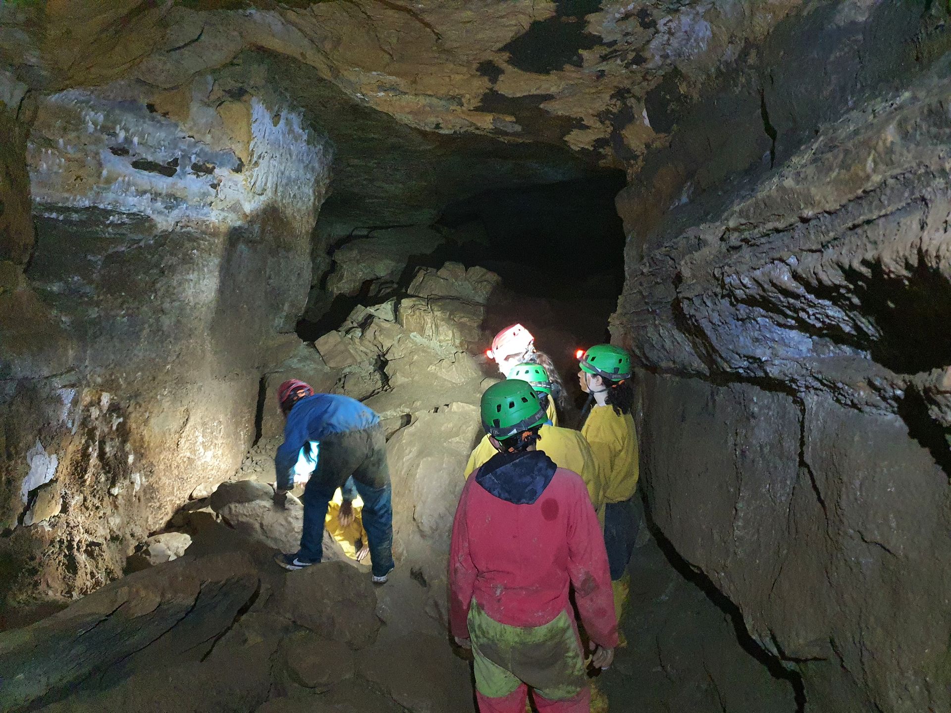 Des personnes casquées explorent un tunnel de grotte sombre