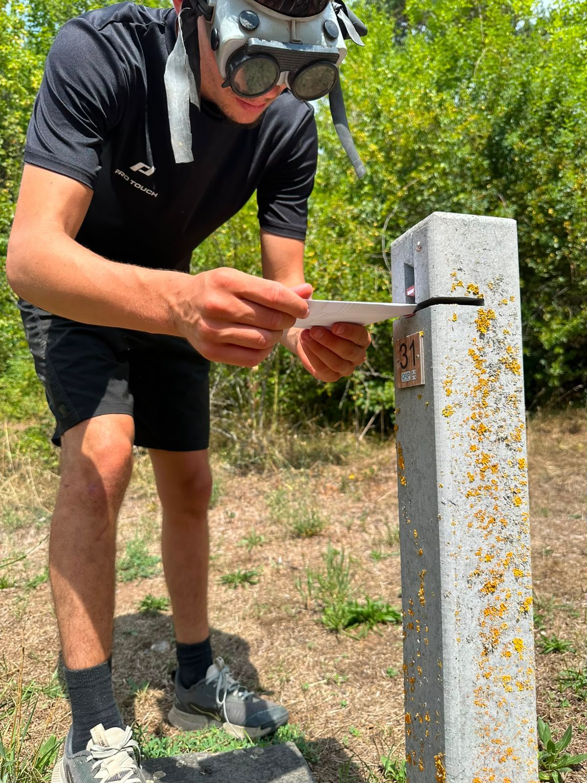 Une personne utilise un couteau pour découper un poteau électrique en béton à l'extérieur par une journée ensoleillée.