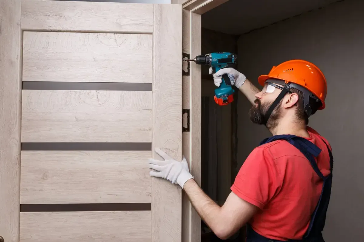 Un hombre está instalando una puerta con un taladro.