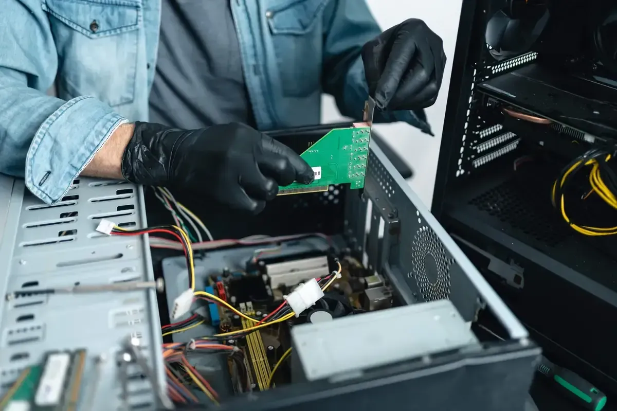 Un hombre que lleva guantes negros está trabajando en una computadora.