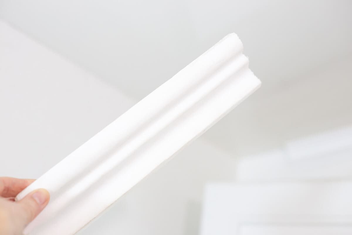 Un hombre está rociando espuma en el alféizar de una ventana.
