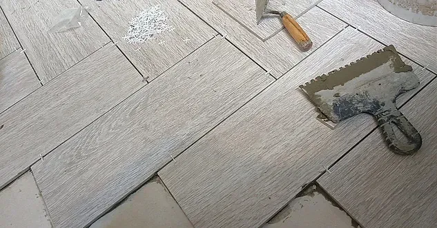 Una paleta y una espátula están colocadas sobre un suelo de baldosas.