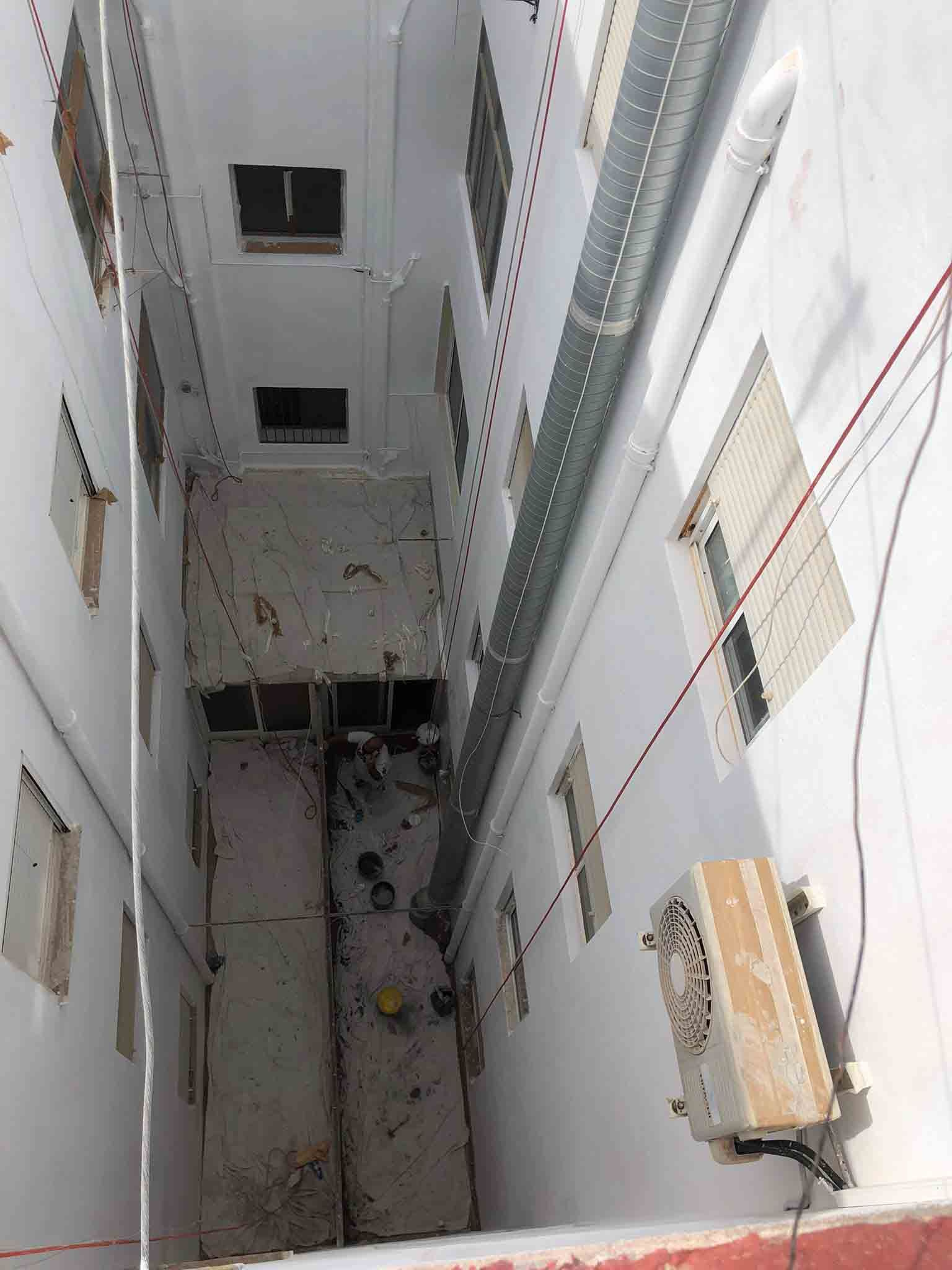 Toma vertical estrecha del hueco exterior de un edificio con tuberías y ventanas.