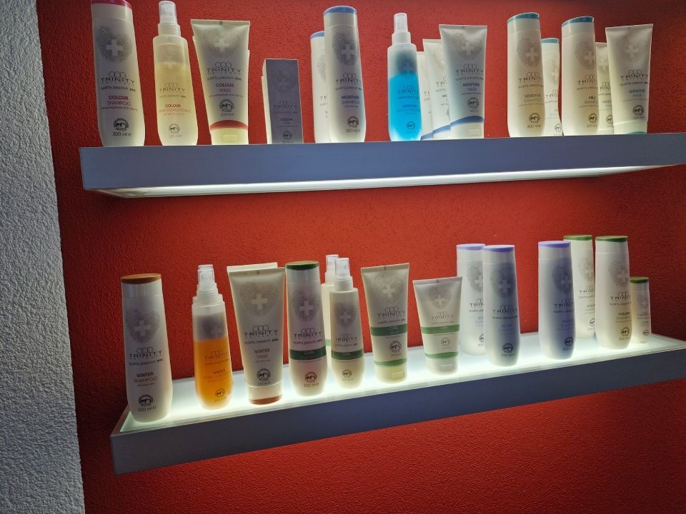 Regale mit verschiedenen Hautpflegeprodukten, die vor einer roten Wand beleuchtet sind.