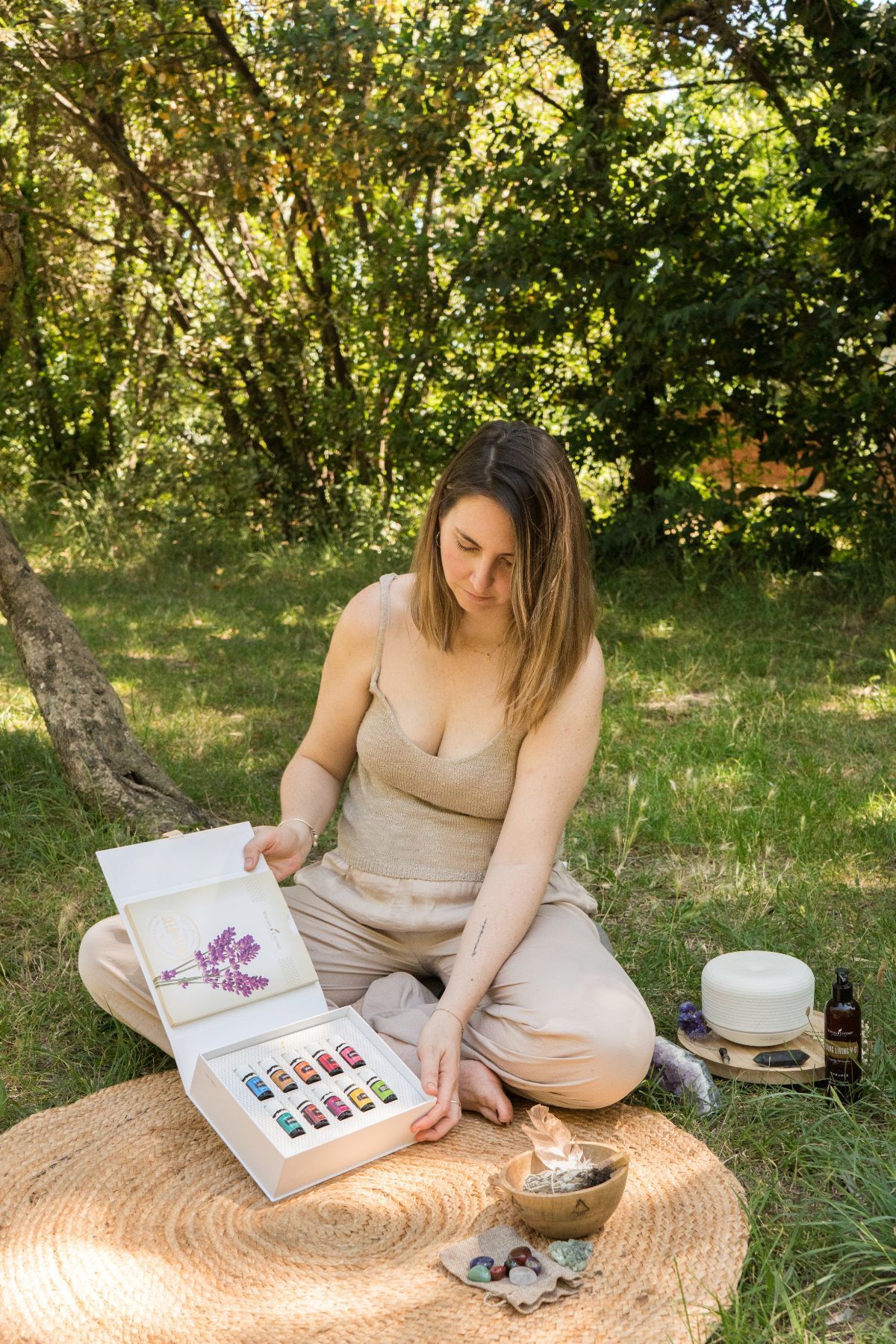 Mujer pintando al aire libre sobre una manta, con paleta de acuarelas y cuaderno de bocetos en un jardín soleado.