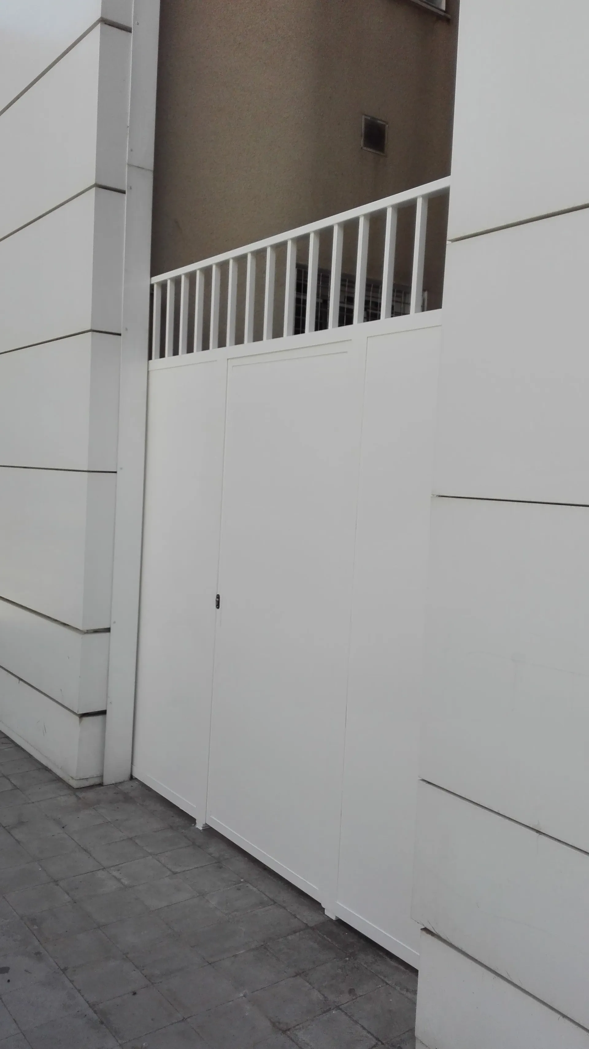 Una valla blanca con barandilla está al lado de un edificio.