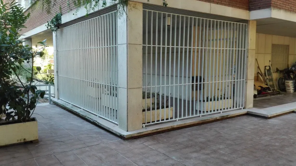Una valla metálica blanca rodea un edificio de ladrillo.