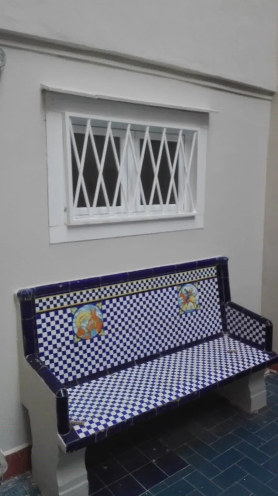 Un banco azul y blanco está sentado frente a una ventana.
